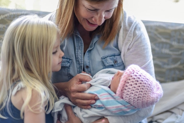 Family gathering around newborn baby girl in hospital recovery room