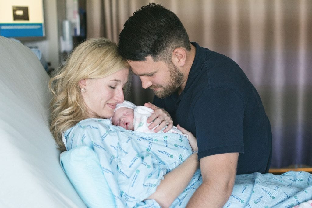 A new mother and father hold her newly adopted newborn.
