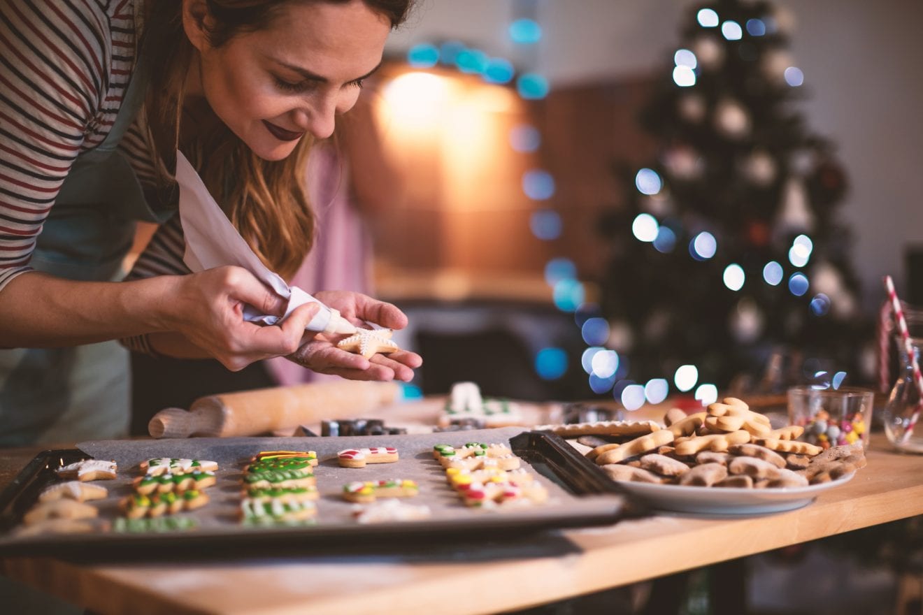 Young woman decorating a Gingerbread cookies for Christmas.
