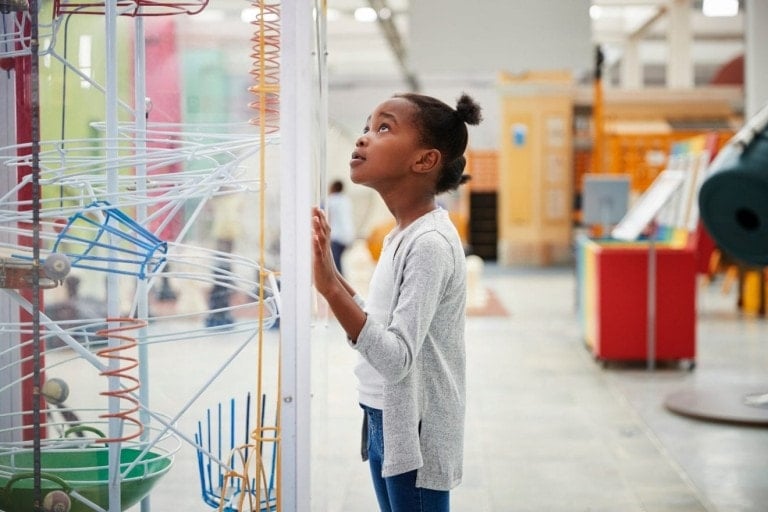 Young girl looking at a science exhibit, close up.