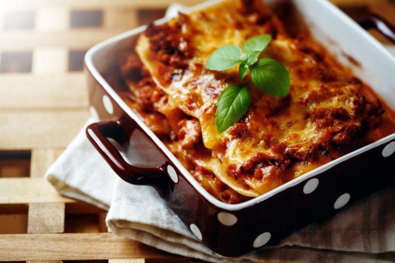 Italian Food. Hot Tasty Freshly Baked Lasagna Served with Basil Herb on Wooden Table.