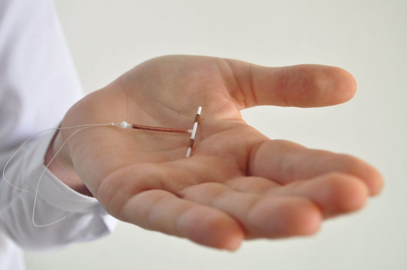Holding an IUD birth control device in hand.
