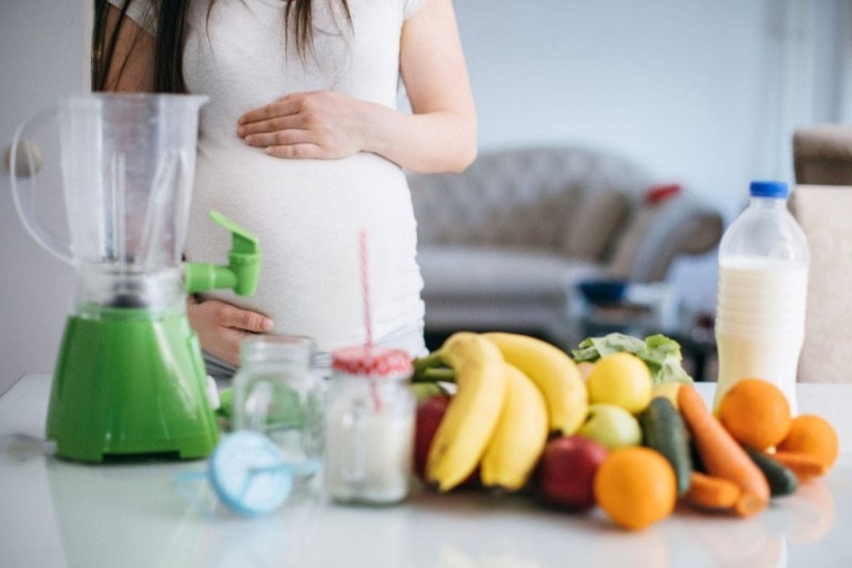 Pregnant woman making fruit juice with food processor
