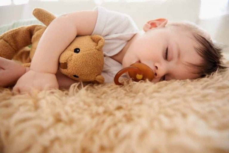 toddler sleeping on floor with pacifier in mouth