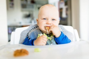 Baby eating in a high chair.