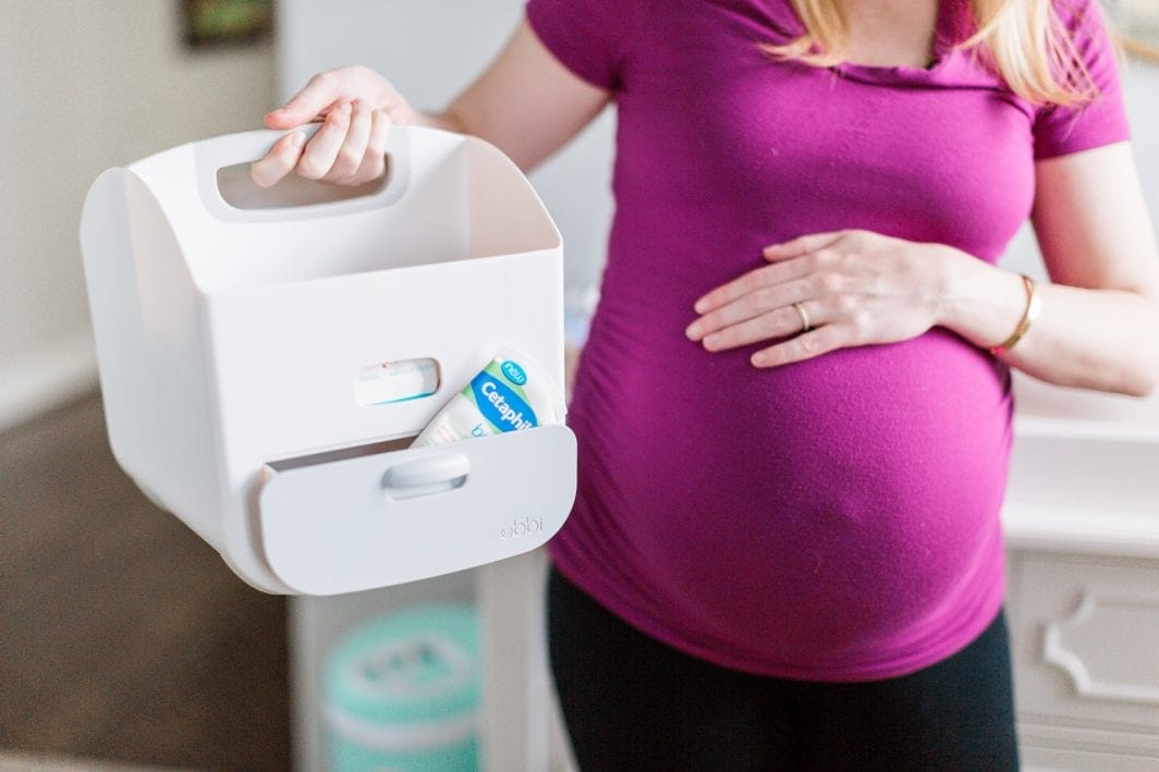 pregnant mom holding a diaper caddy