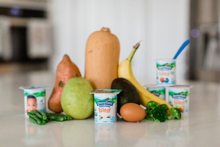 Stonyfield yogurt and fruits and vegetables sitting on a kitchen counter.