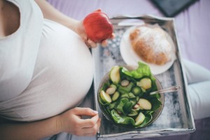 pregnant woman sitting with tray of food