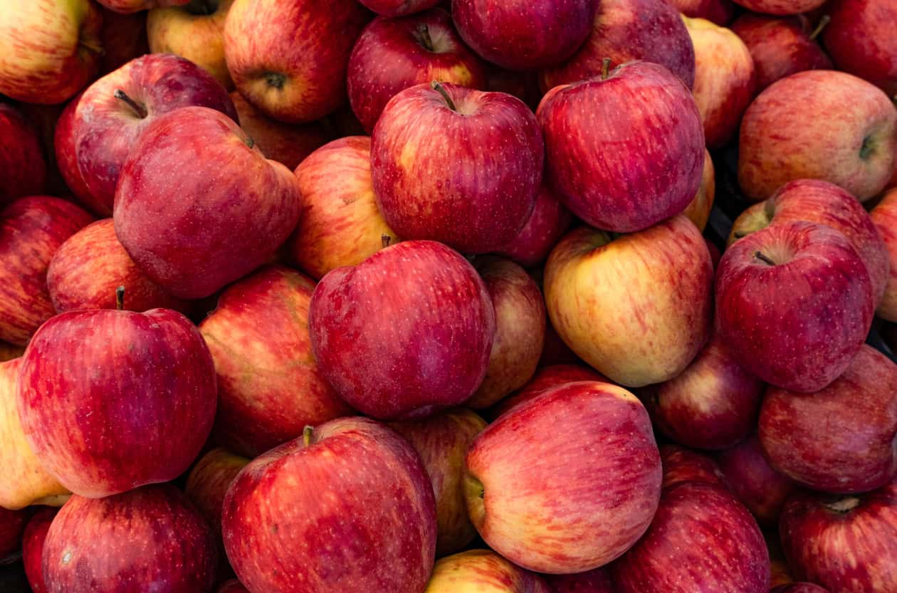 A close-up image of a large pile of red apples with varying shades and yellow highlights, perfect as healthy snacks for pregnancy. The apples appear fresh and shiny, filling the entire frame, offering an ideal choice for nutritious and vibrant healthy pregnancy meals.
