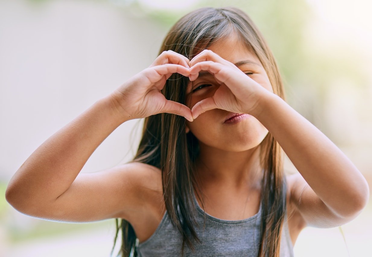 Portrait of a little girl making a heart gesture with her hands