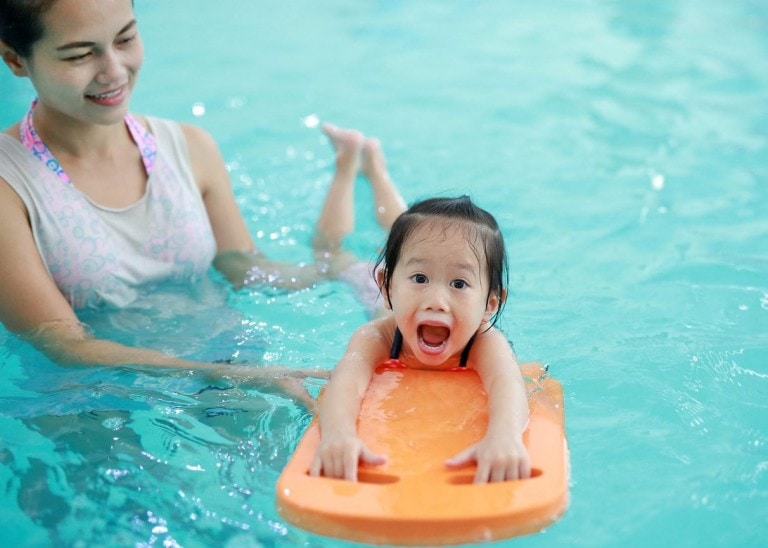 woman teaching toddler how to swim