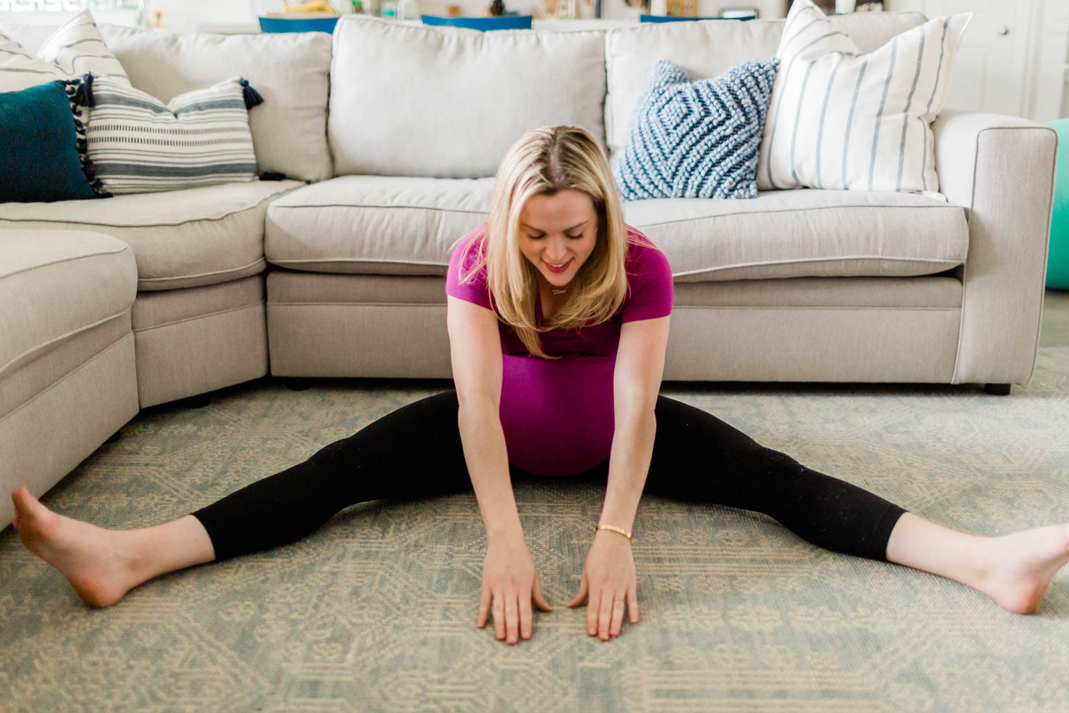 A pregnant woman doing the seated straddle stretch.