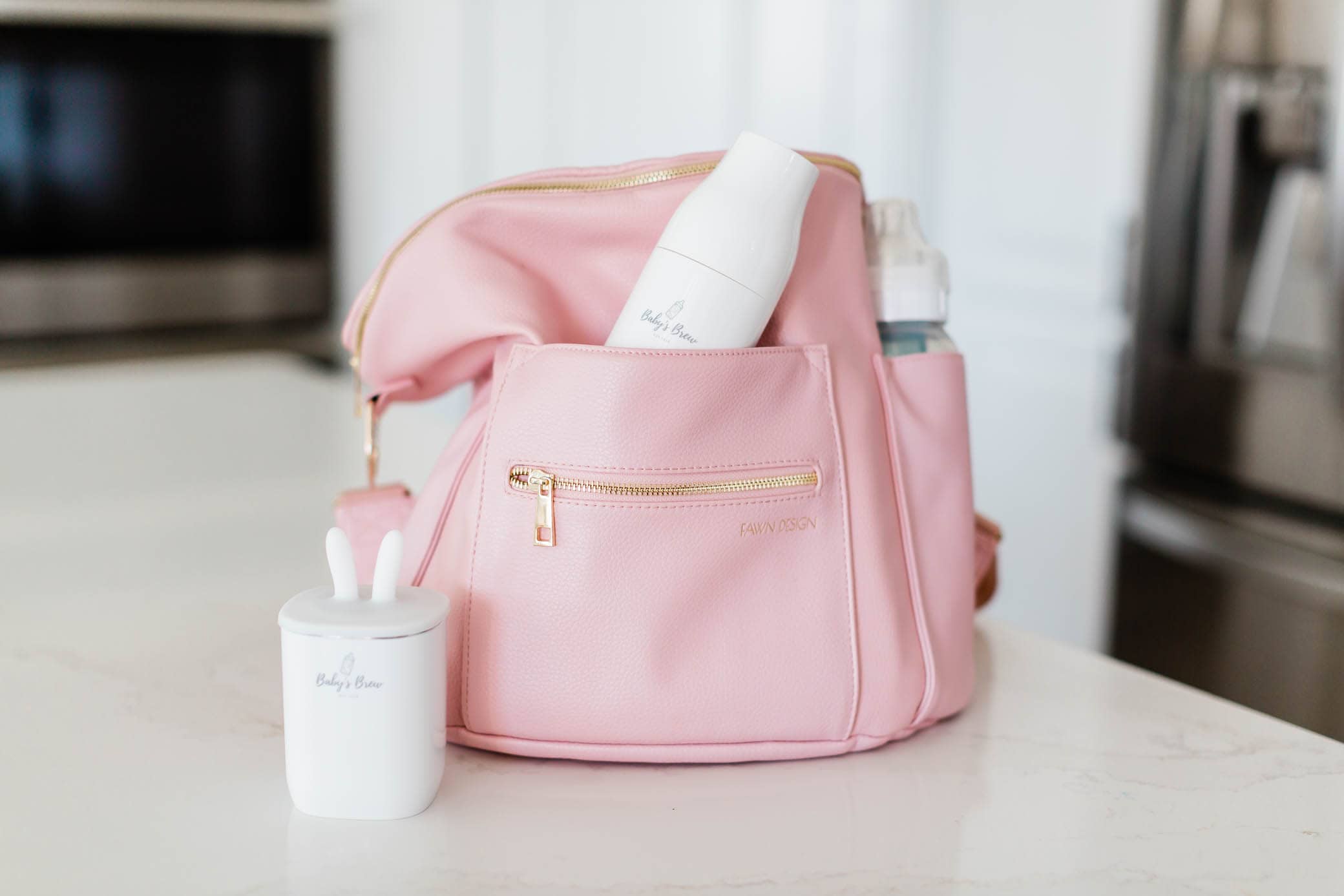 Baby's Brew products inside a pink diaper bag sitting on a kitchen counter.
