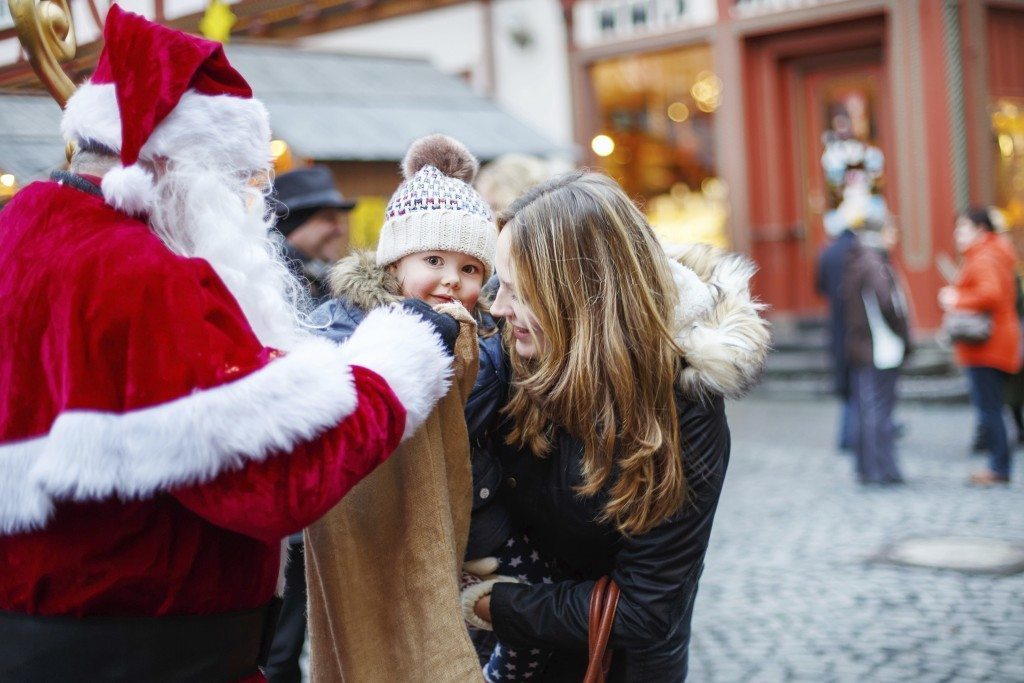 Little toddler girl with mother on Christmas market.