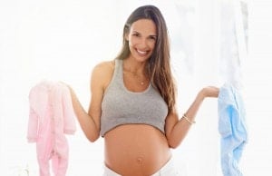 Shot of a pregnant woman holding a pink and blue onesie