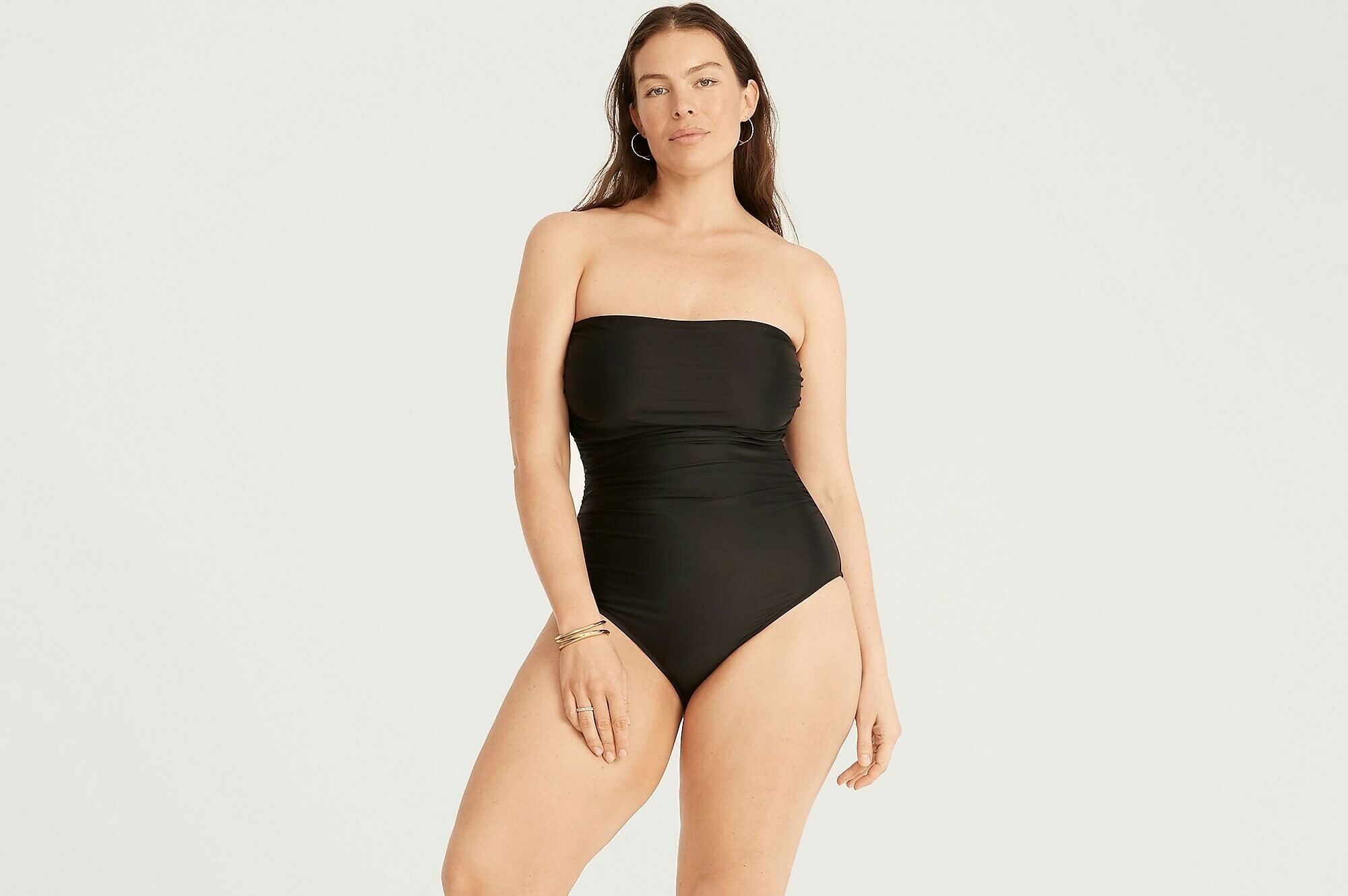 A woman is standing and wearing a one-piece swimsuit.