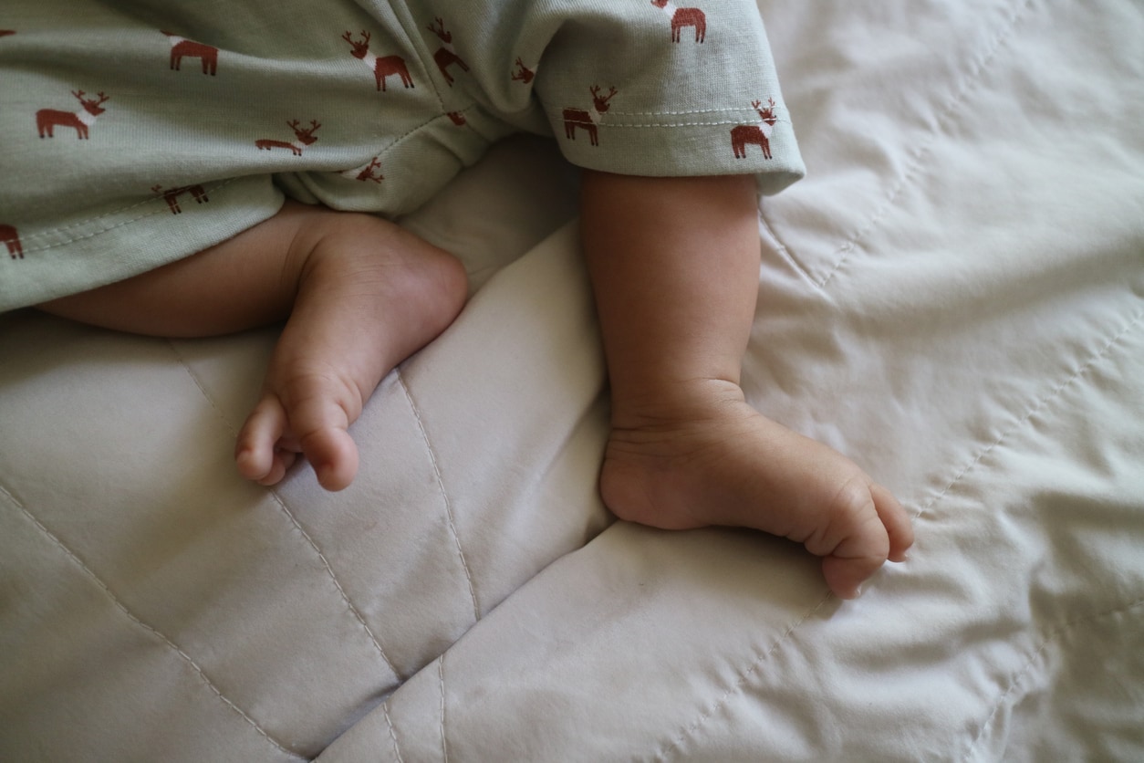 a photo of a cute feet of a newborn baby on a white mattress