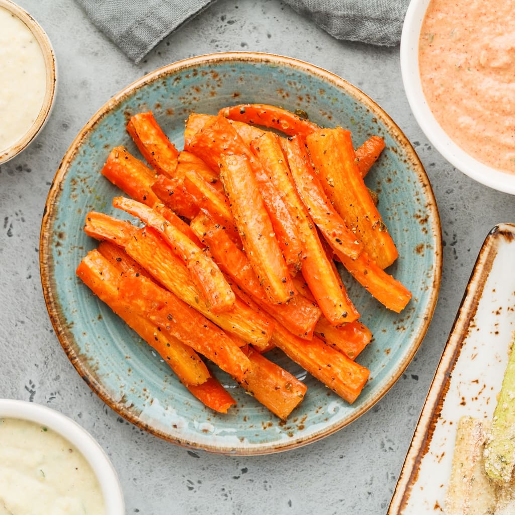 Baked season carrot sticks with sauce and hummus. Vegetarian healthy food. Flat lay, top view.