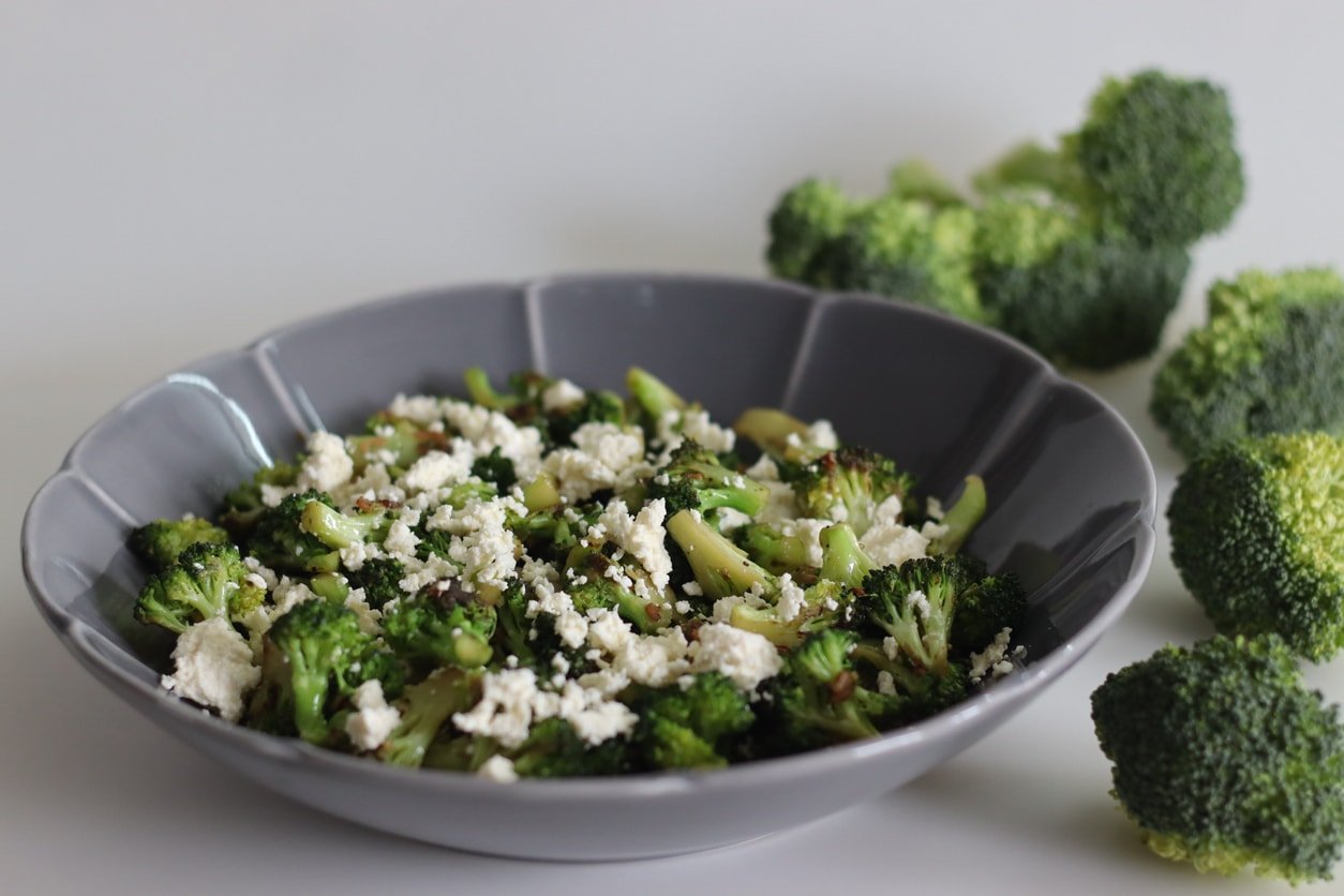 Broccoli with feta cheese. Sauteed broccoli florets sprinkles with served with crumpled feta cheese. Healthy dish to start the meal. Shot on white background.