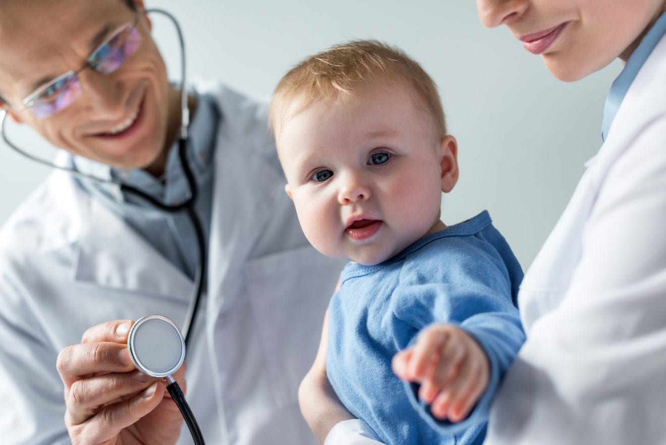 Pediatrician checking breath of adorable little baby.