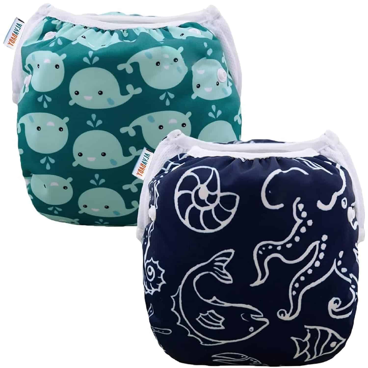 Here is your text with all single and double quote characters removed: Two reusable swim diapers are shown—summer must-haves for your little one. One is teal with a cartoon whale pattern, and the other is navy blue with white sea creature illustrations. Both feature white trim and elastic bands for a snug fit.