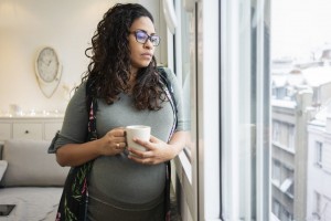 Pregnant woman drinking coffee at home.