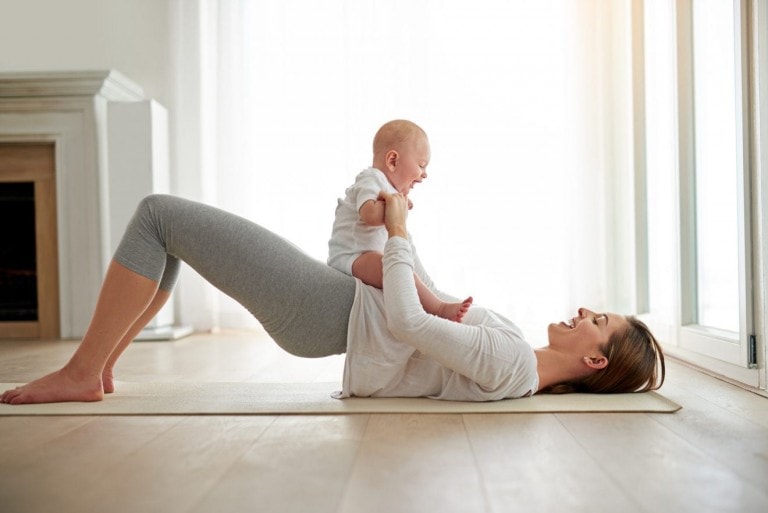 Young woman working out with her baby boy at home