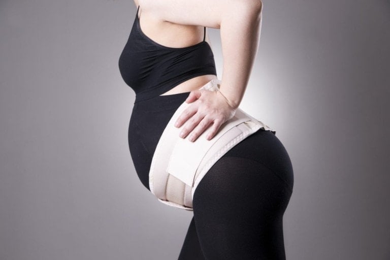 Young caucasian pregnant woman with pregnancy support belt