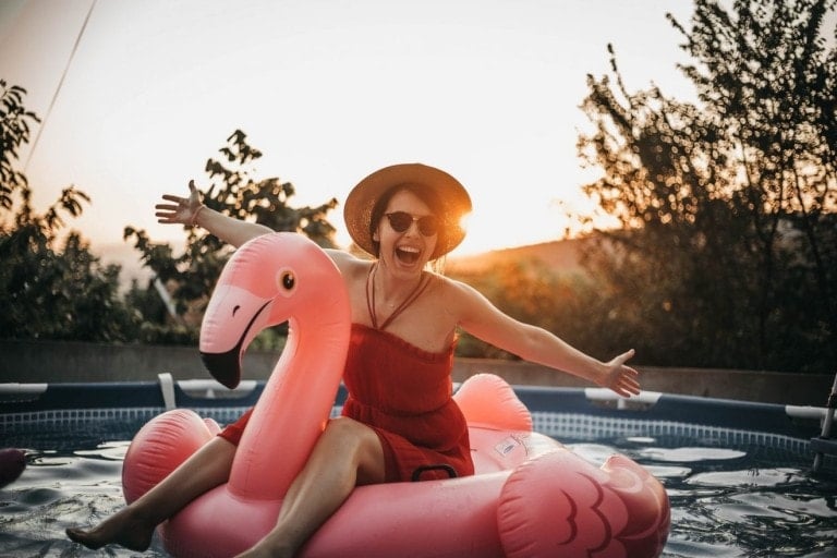 Mom in the pool sitting on an inflatable flamingo pool floatie