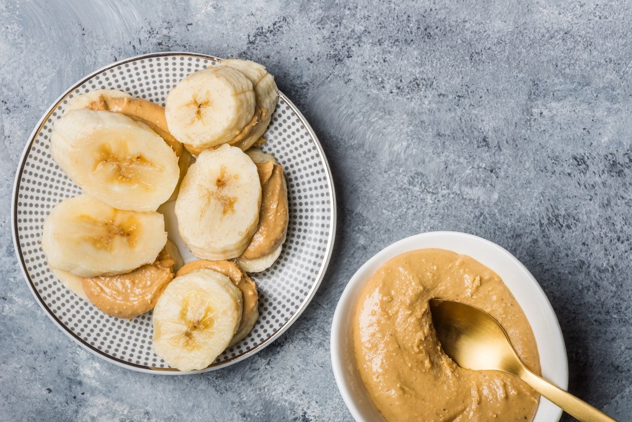 Light Healthy Snack made from Banana Slices and Cashew Butter on Grey Background