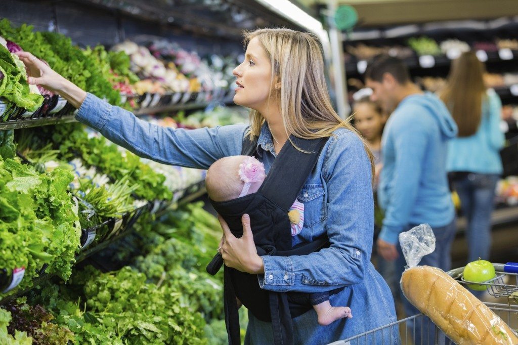 Young-mom-wearing-baby-in-carrier-while-shopping-for-produce-000080785629_Large