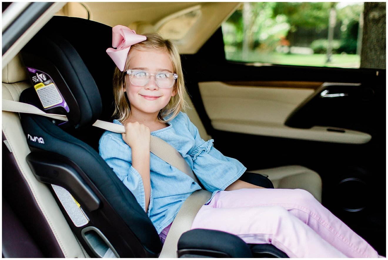 Young girl sitting in the NUNA Exec all-in-one car seat as a booster.