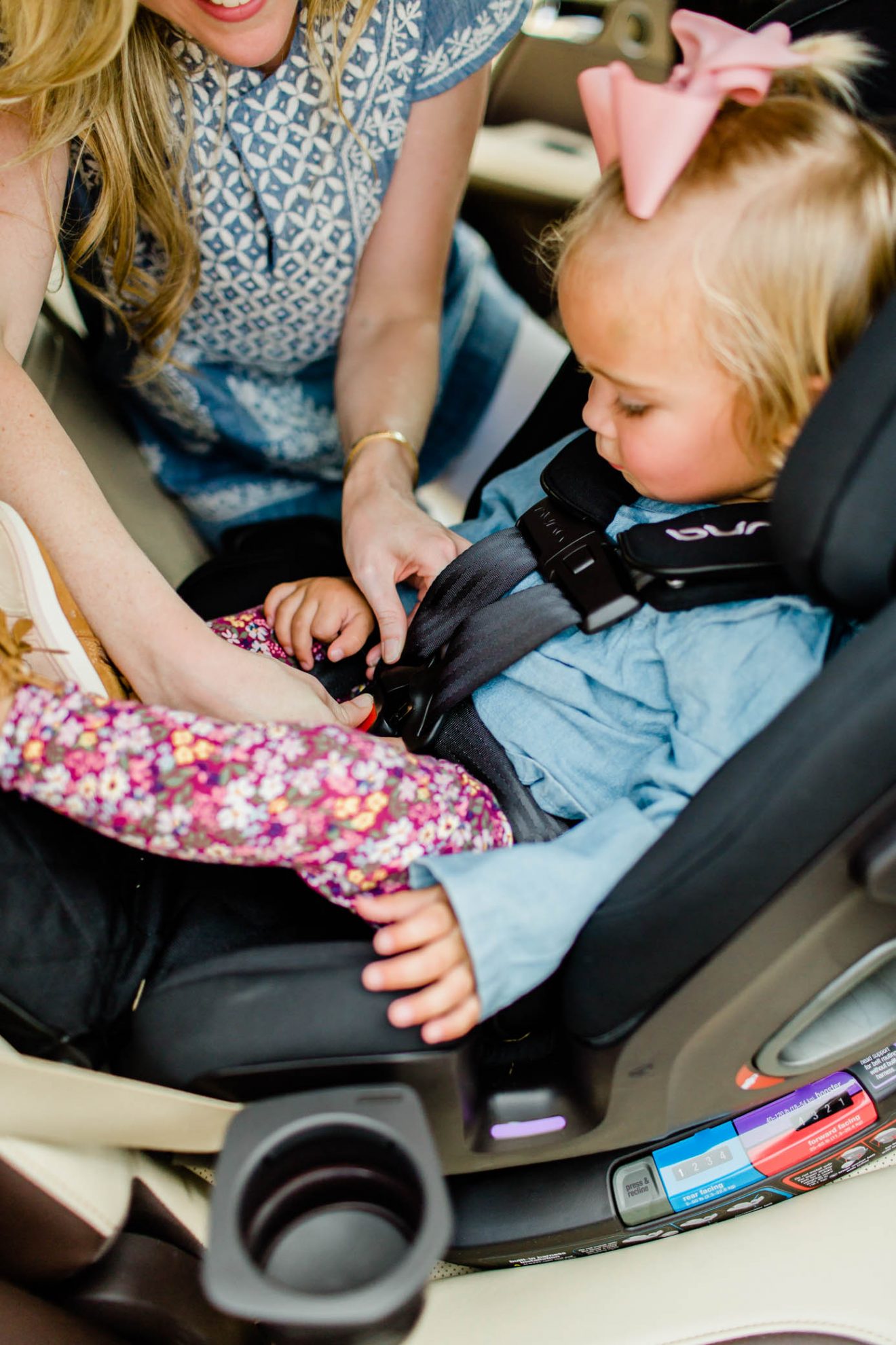 Buckling in a toddler girl into the NUNA EXEC all-in-one car seat.