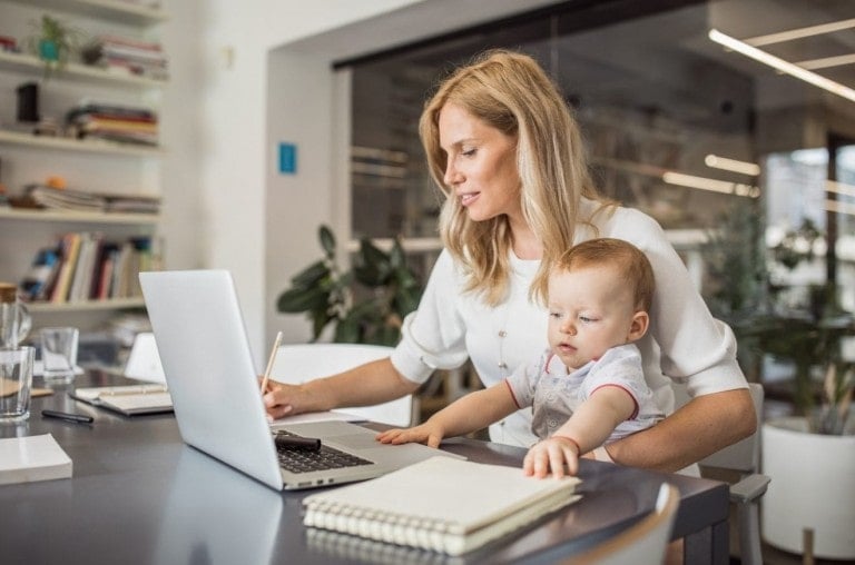 Single mother with baby working in office.