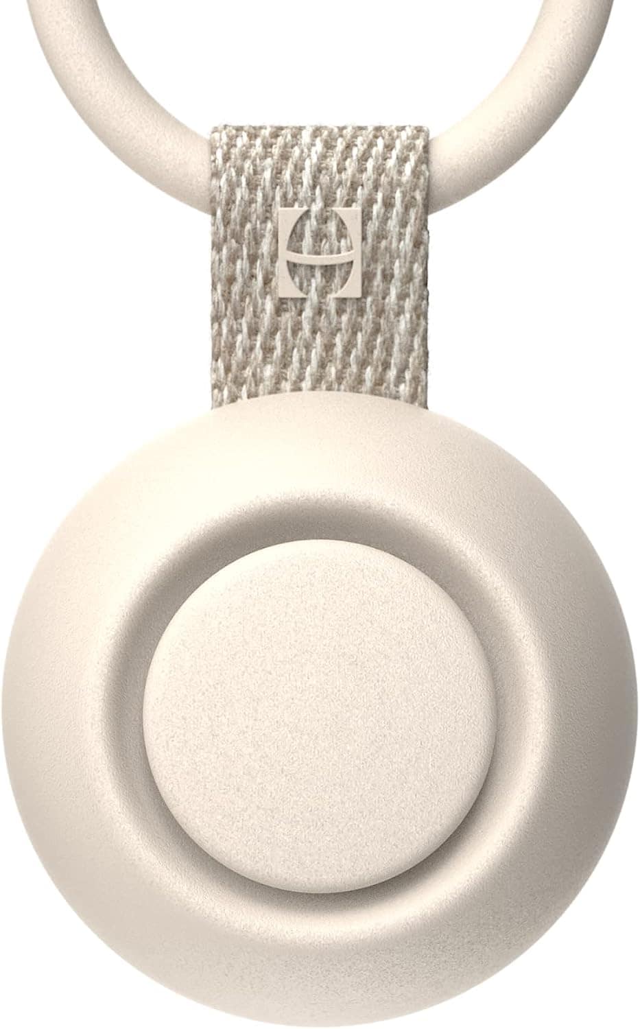 Close-up image of a round, beige keychain holder with a looped fabric strap and a metal clip. The fabric strap has a square metallic logo, likely indicating the brand. This minimalistic and modern design could be a thoughtful addition to your postpartum essentials.