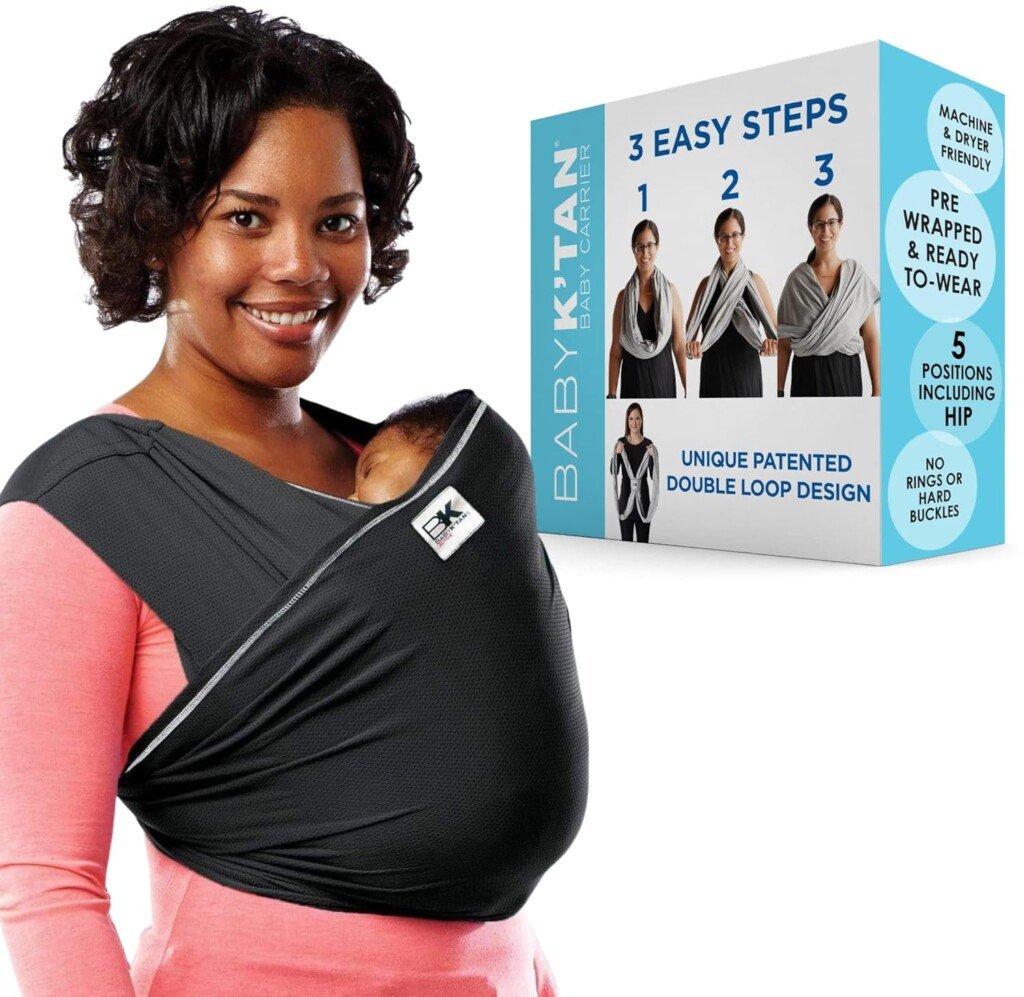 A woman is shown wearing a black Baby K'tan baby carrier with a baby inside. Next to her is the product packaging, highlighting features such as "3 Easy Steps," "No Rings or Hard Buckles," and "5 Positions Including Hip." It's the perfect accessory for postpartum essentials.