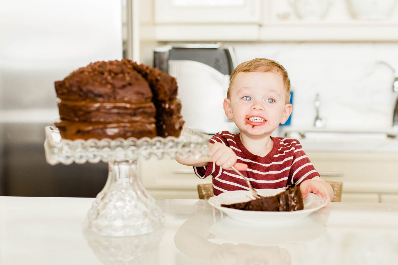 Toddler boy enjoying a slice of chocolate cake.