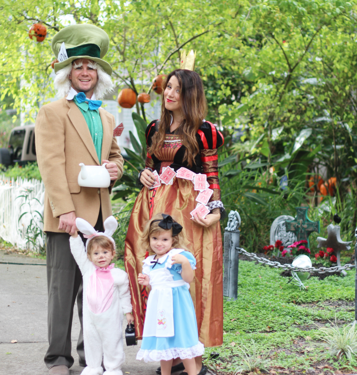 family dressed up as characters from alice in wonderland: the mad hatter, the queen of hearts, the white rabbit, and alice