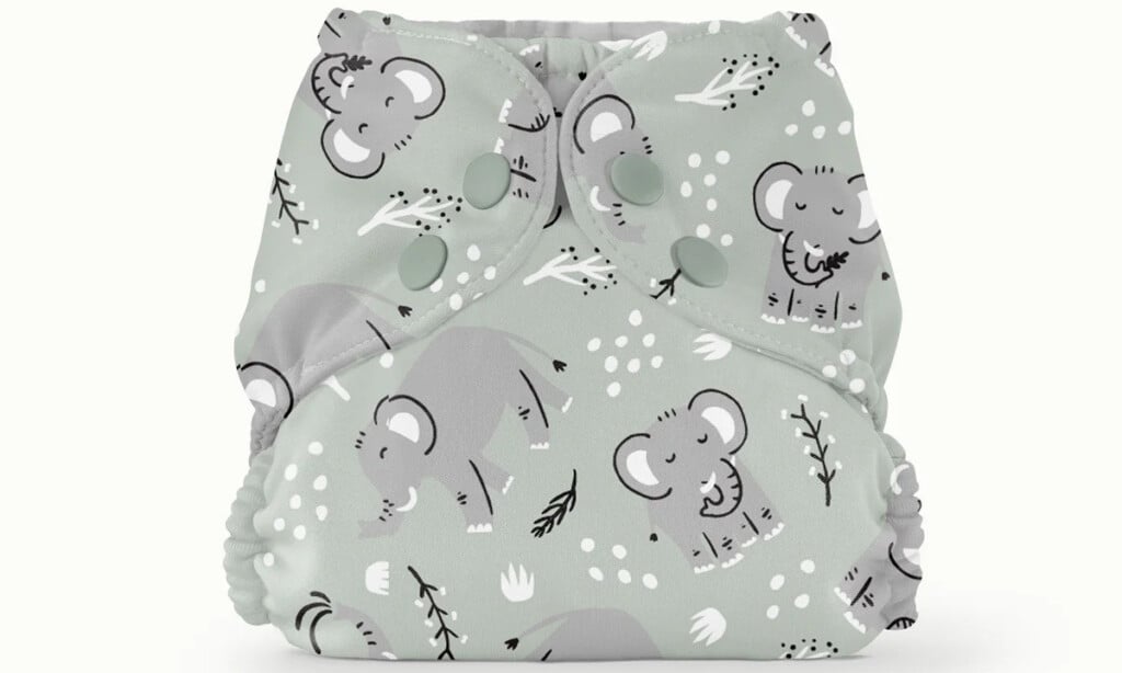 A reusable cloth diaper with a light green background and illustrations of elephants, leaves, and small shapes. An essential for postpartum recovery, the diaper features plastic snap buttons for an adjustable fit.