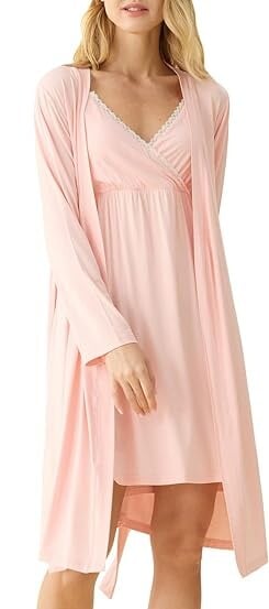 A person recovering from a c-section gracefully wears a light pink nightgown with a matching robe. The delicate lace detail at the neckline and an empire waist offer comfort as essentials. Barefoot against a plain white background, they embody serene elegance.