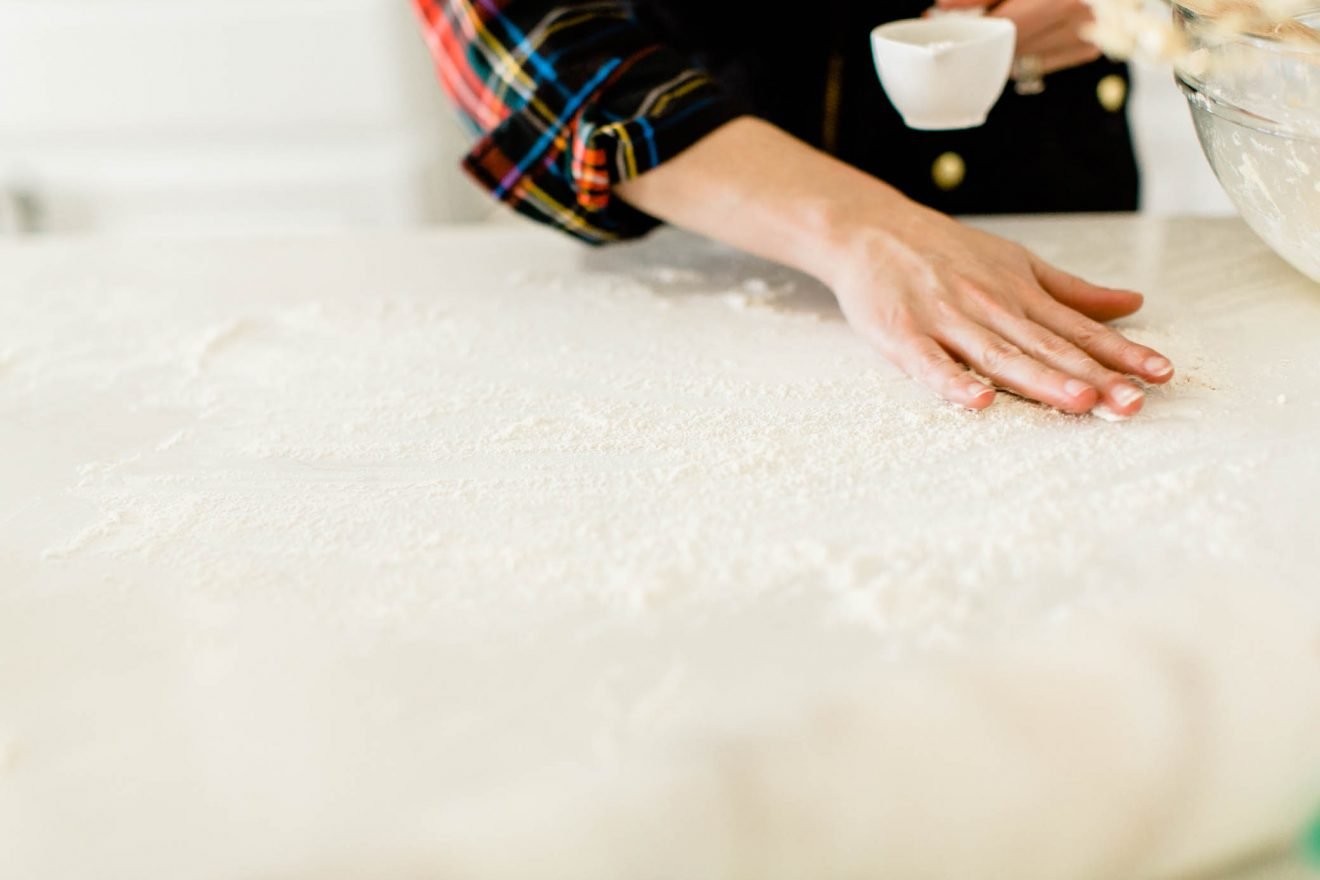 Flouring a kitchen counter to begin rolling dough.