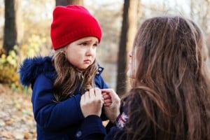 Scared daughter holding mother's hands in autumn park. Child girl express sad emotions, complain about their own problems.