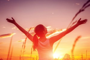 Free and happy woman raises arms against the sunset sky. Harmony and balance concept.