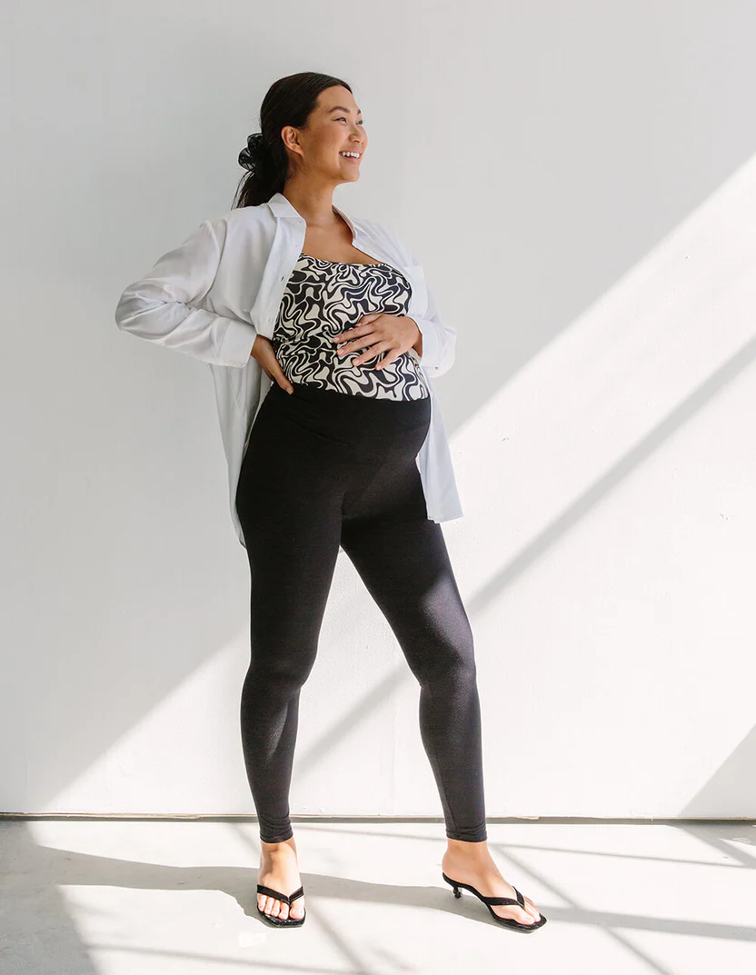 Woman in black maternity leggings with printed shirt and white button down