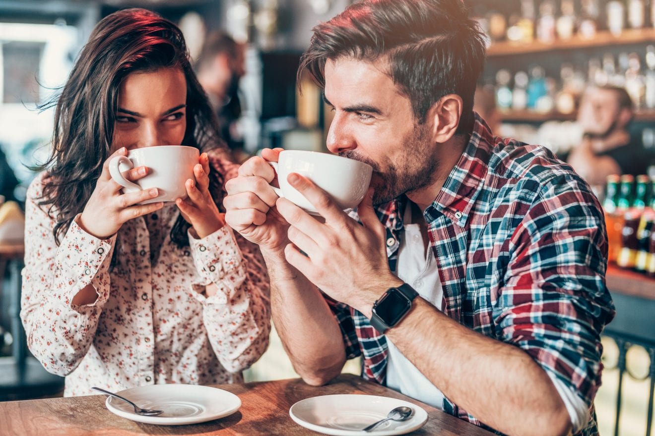 Beautiful young couple drinking coffee and looking each other