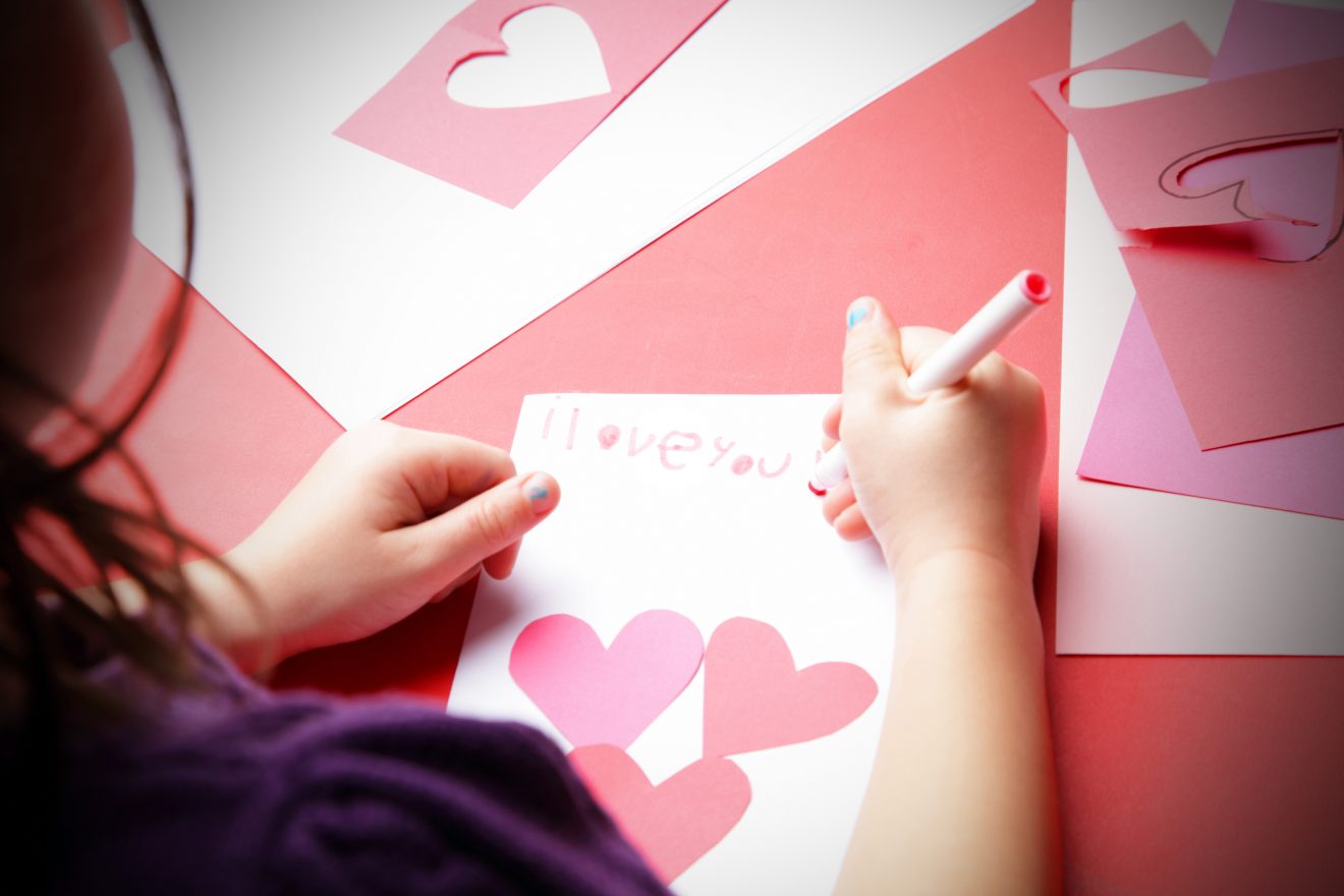 A young girl makes the finishing touches to her "I love you!" card. Perhaps a Valentine's Day card 