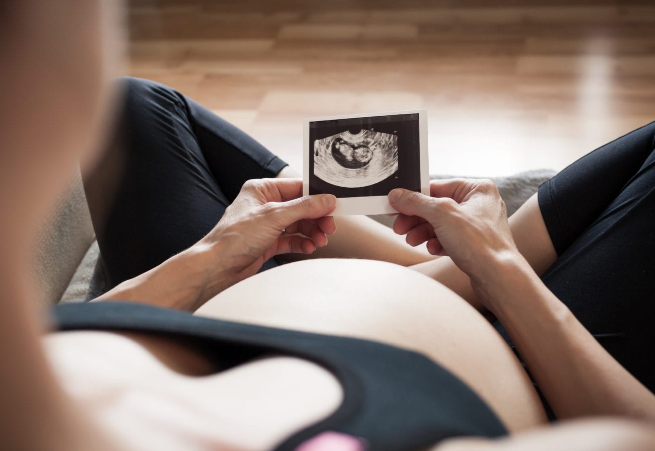 Beautiful pregnant woman looking at ultrasound pictures.