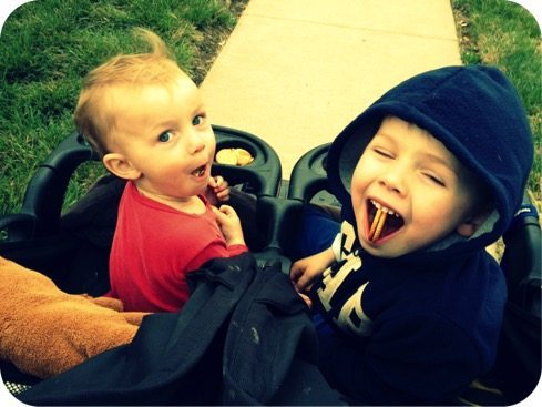 two boys riding side by side in a stroller