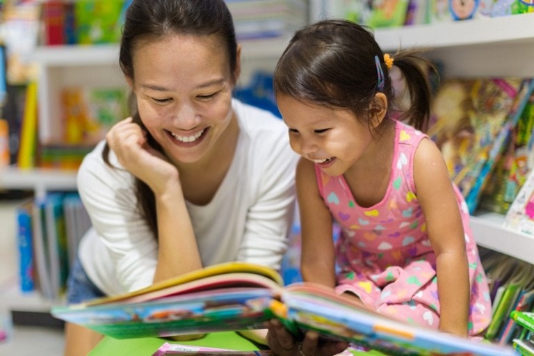 Parent and child reading books together for homeschooling.