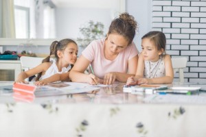 Mother helping daughters with homework at the table.